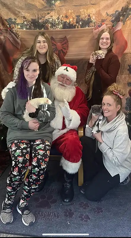 Group of clients holding small animals and posing with Santa at the Santa Paws event in Carol Stream
