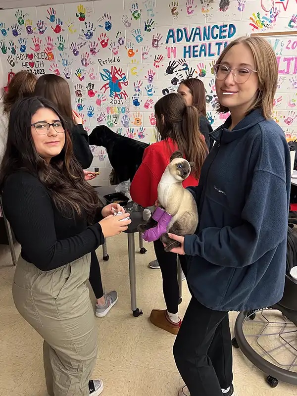 Student holding a cat with a bandaged leg during a veterinary education visit in Carol Stream