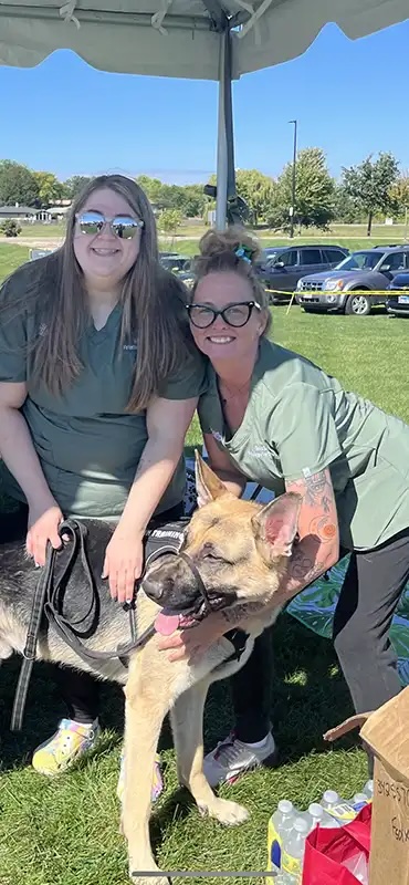 Two veterinary staff members petting a German Shepherd at the charity dog show in Carol Stream