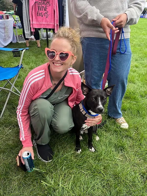 Veterinary technician crouching with a black dog at the Annual Charity Dog Show in Carol Stream