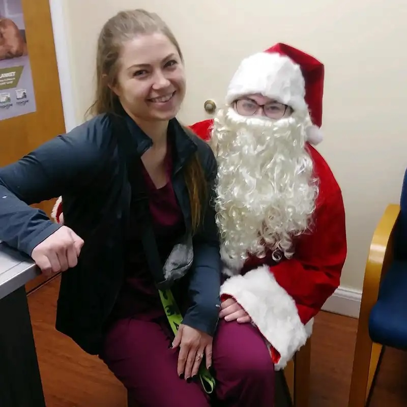 Veterinary staff member posing with Santa at the Santa Paws event in Carol Stream