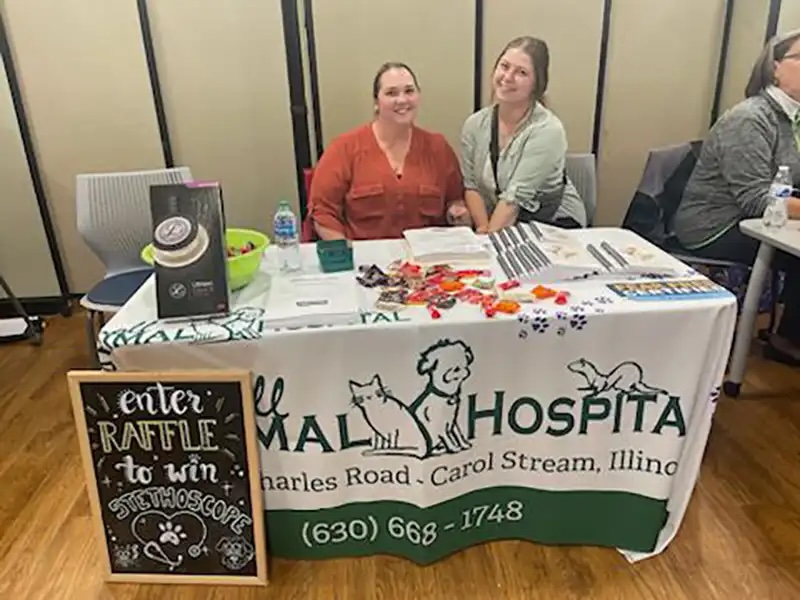 Two veterinary team members staffing an information booth at a community expo in Carol Stream